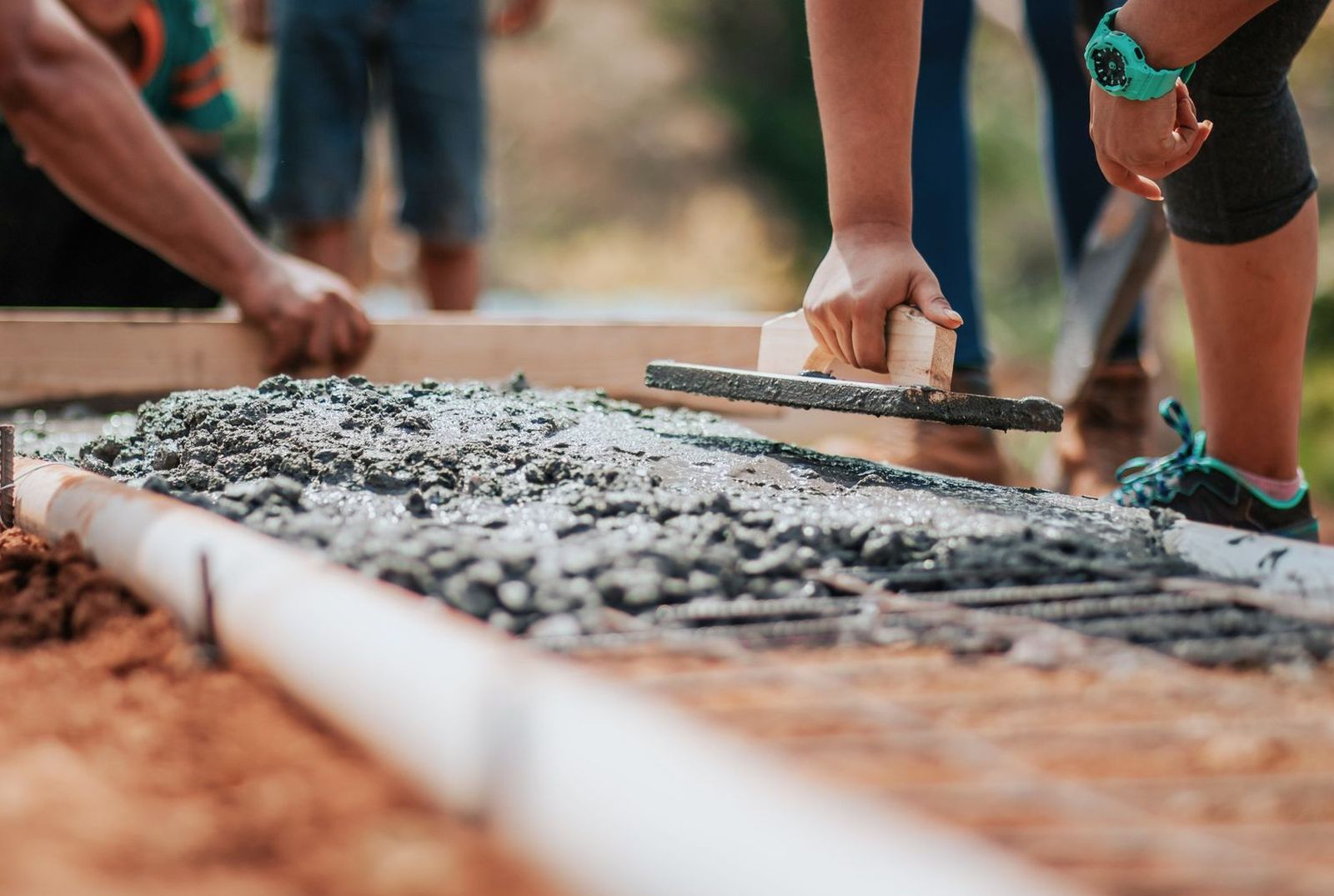Concrete crew hand-floating a freshly poured slab inside timber forms over rebar