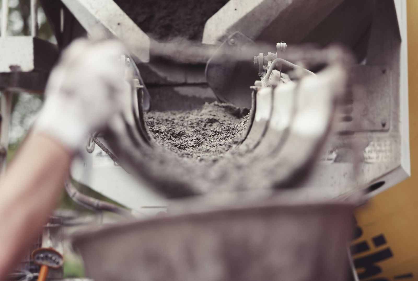 Wet concrete running down a mixer truck chute into a wheelbarrow on a job site