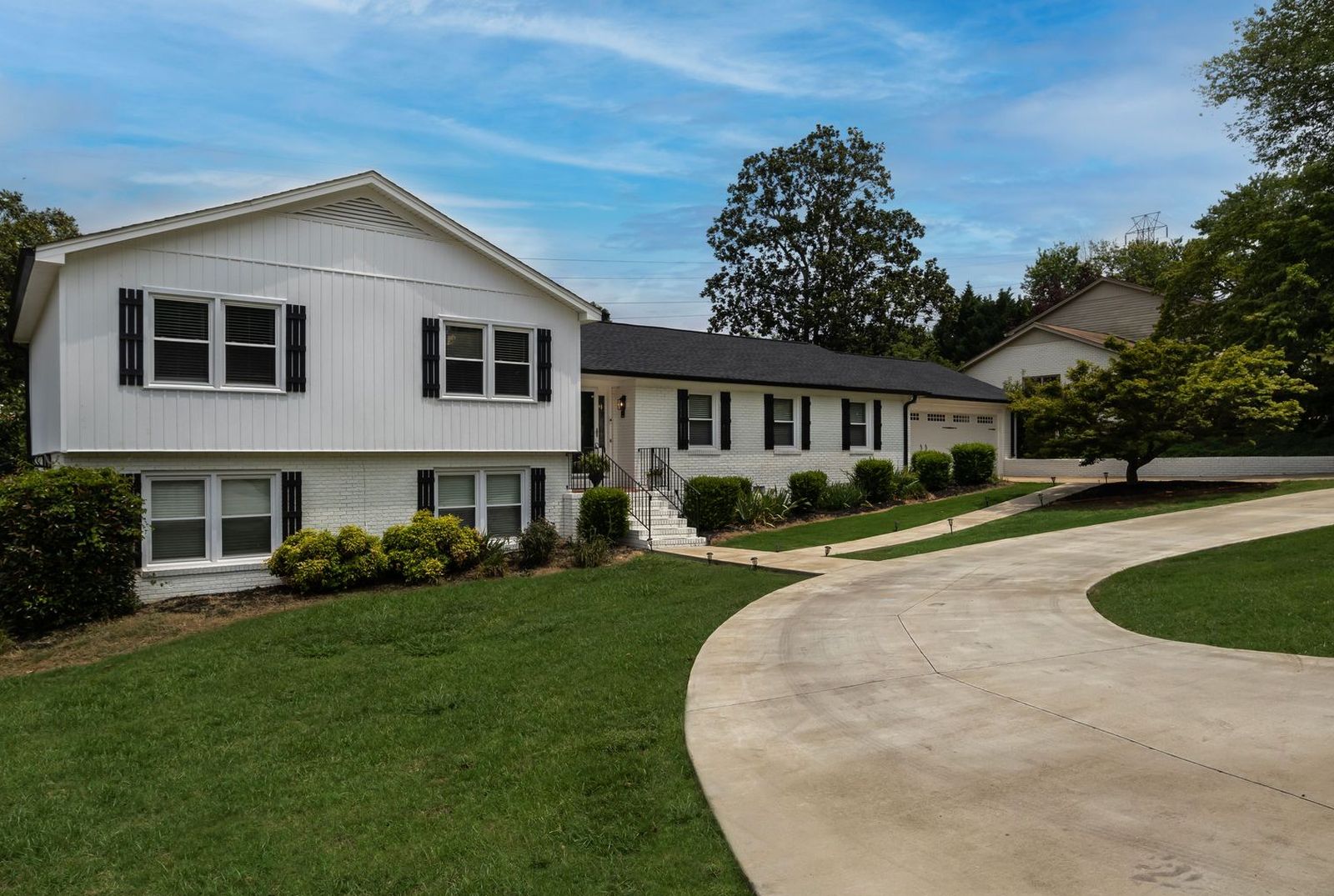 Wide curving concrete driveway leading up to a two-car garage