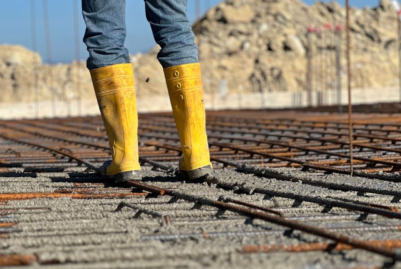 Worker standing on a tied rebar mat laid out over a prepared slab base before the pour
